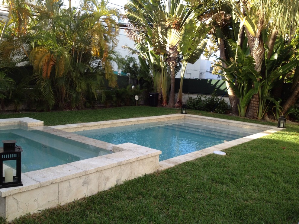 Mid-sized tropical backyard rectangular lap pool in Miami with a hot tub and natural stone pavers.