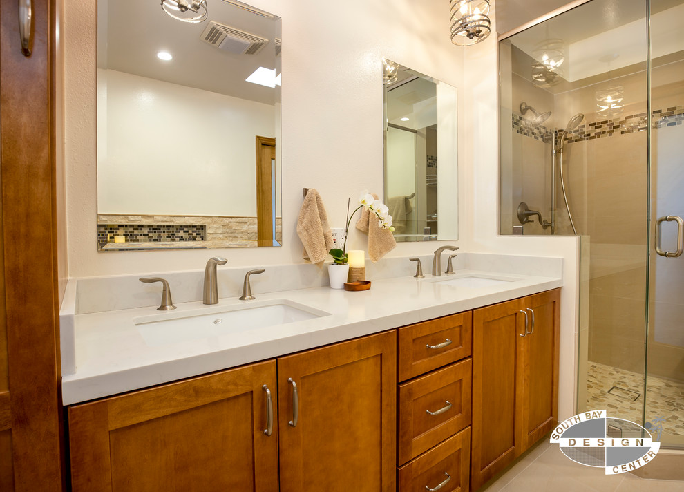Photo of a mid-sized transitional master bathroom in Los Angeles with shaker cabinets, medium wood cabinets, a hot tub, a corner shower, a one-piece toilet, beige tile, stone tile, beige walls, porcelain floors, an undermount sink, engineered quartz benchtops, beige floor and a hinged shower door.