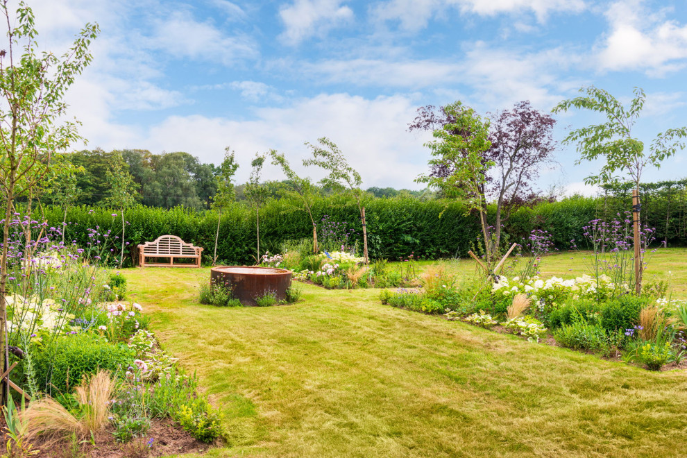 Idée de décoration pour un grand jardin arrière champêtre avec un massif de fleurs et une exposition ensoleillée.