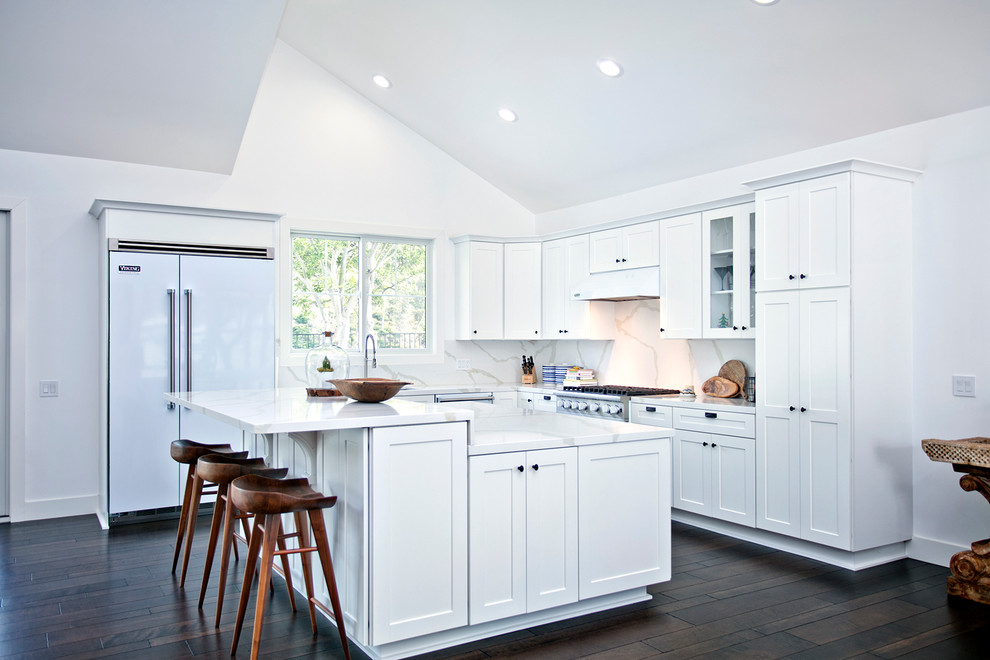 Transitional l-shaped dark wood floor kitchen photo in Orange County with shaker cabinets, white cabinets, white backsplash, white appliances and an island
