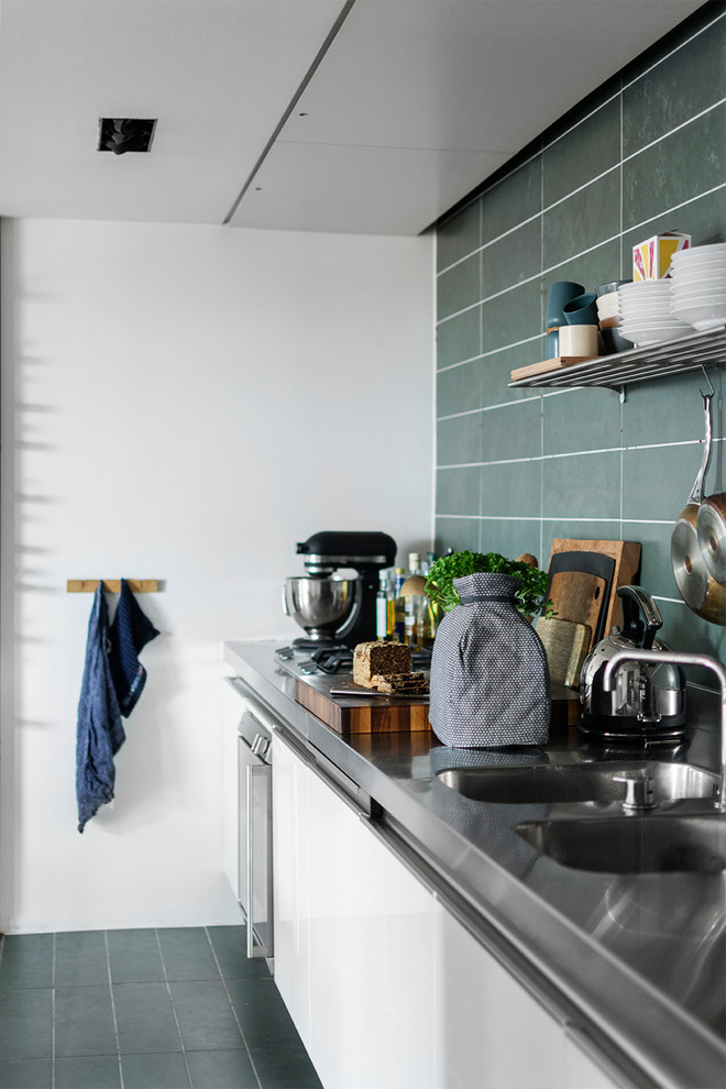 Inspiration for a scandinavian kitchen in Aarhus with a double-bowl sink, flat-panel cabinets, white cabinets, stainless steel benchtops, green splashback, stainless steel appliances, green floor and grey benchtop.
