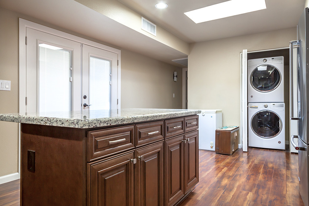 Inspiration for a mid-sized transitional l-shaped laminate floor and brown floor enclosed kitchen remodel in Phoenix with an undermount sink, shaker cabinets, medium tone wood cabinets, granite countertops, multicolored backsplash, stone slab backsplash, stainless steel appliances and an island