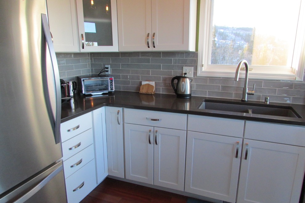 Inspiration for a mid-sized transitional l-shaped medium tone wood floor and brown floor eat-in kitchen remodel with a double-bowl sink, recessed-panel cabinets, white cabinets, gray backsplash, stainless steel appliances, an island and subway tile backsplash