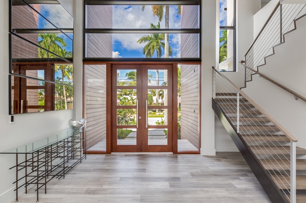 Photo of a mid-sized modern foyer in Miami with white walls, light hardwood floors, a double front door, a glass front door and grey floor.