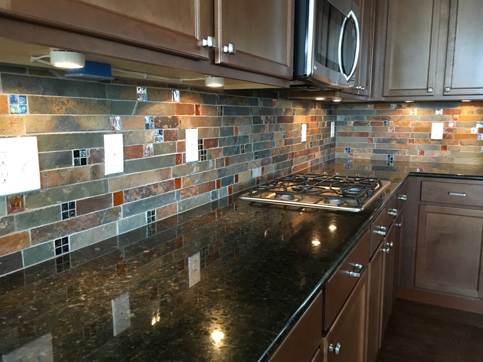 Inspiration for a country kitchen in Denver with recessed-panel cabinets, dark wood cabinets, granite benchtops, multi-coloured splashback, slate splashback, stainless steel appliances, dark hardwood floors and brown floor.