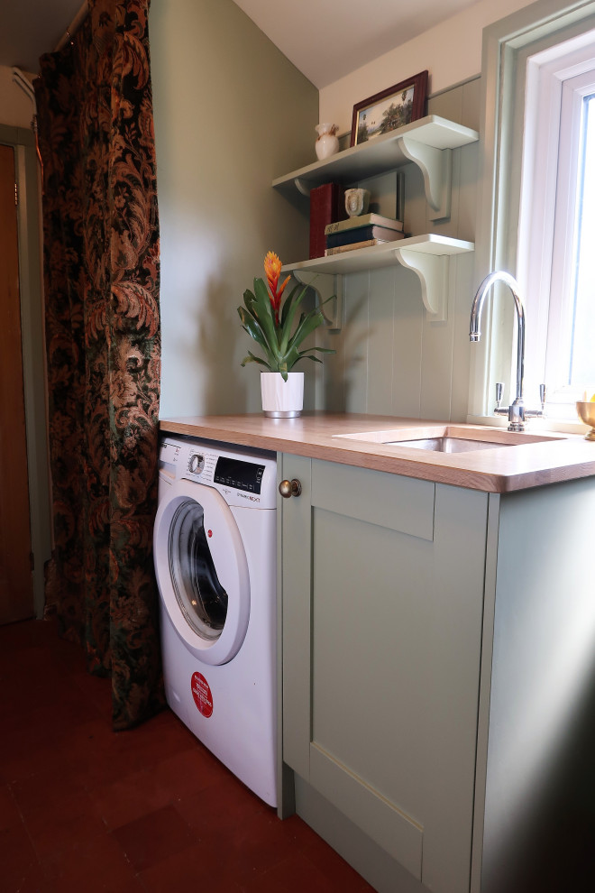 Foto di una piccola lavanderia multiuso classica con lavello a vasca singola, ante in stile shaker, ante verdi, top in legno, pareti beige, pavimento in terracotta, pavimento rosso e top marrone