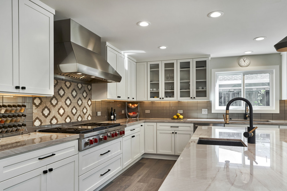 Photo of a large modern u-shaped open plan kitchen in San Francisco with an undermount sink, shaker cabinets, white cabinets, quartzite benchtops, metallic splashback, glass tile splashback, stainless steel appliances, medium hardwood floors, with island, brown floor and beige benchtop.