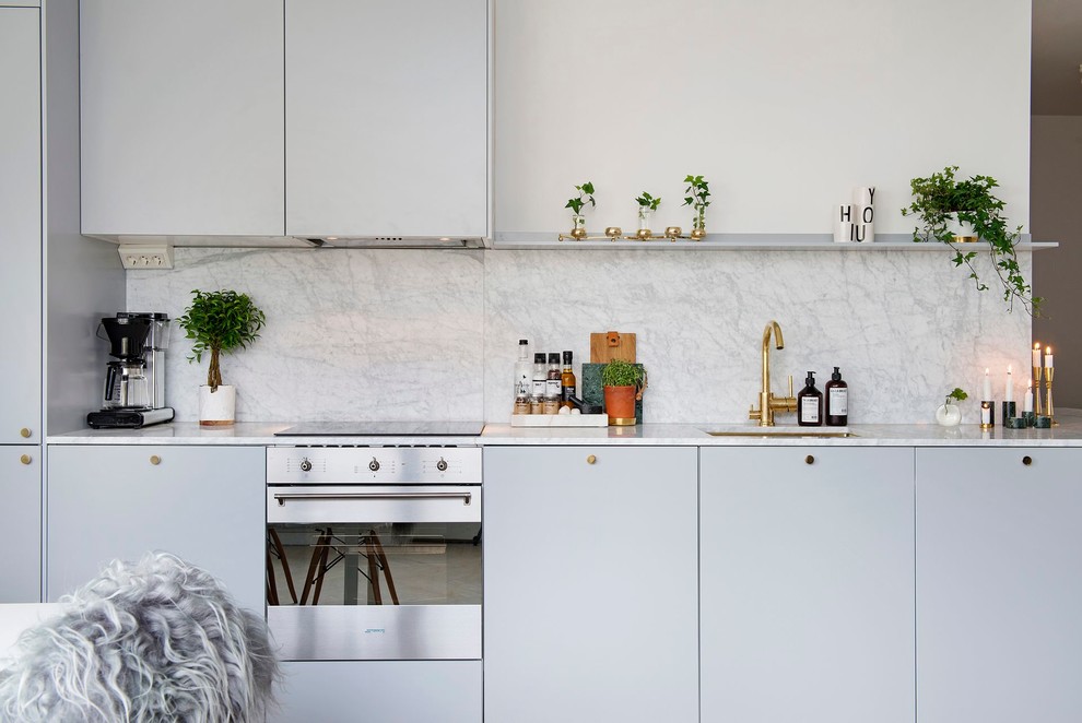 Scandinavian single-wall kitchen in Stockholm with flat-panel cabinets, grey cabinets, marble benchtops, grey splashback, white appliances, no island and an undermount sink.