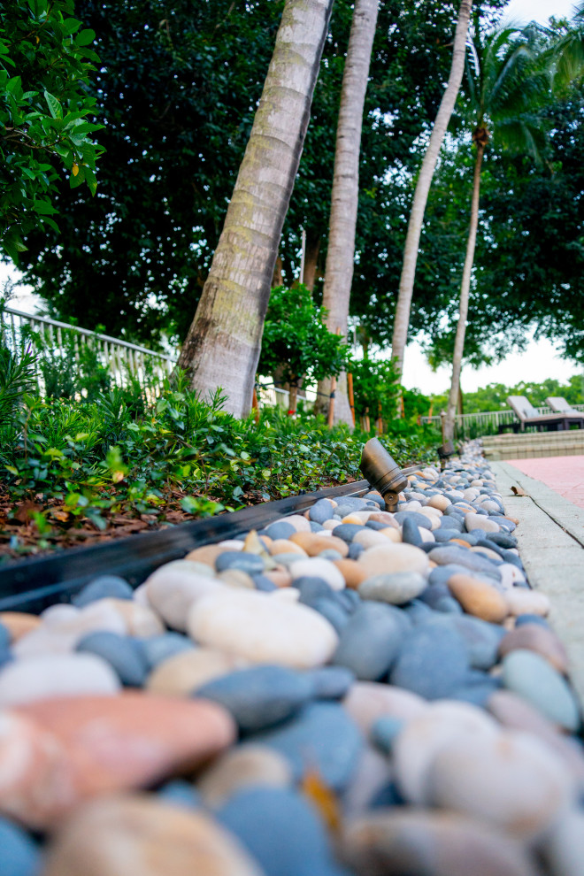 Photo of a large traditional backyard full sun formal garden for summer in Miami with with lawn edging, mulch and a metal fence.