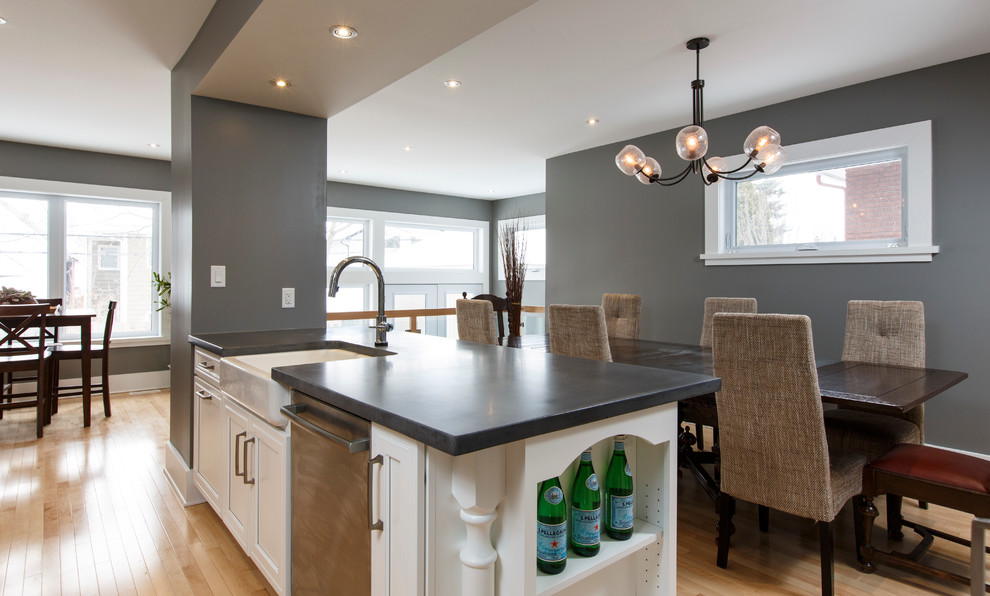 Photo of a traditional galley eat-in kitchen in Ottawa with a farmhouse sink, recessed-panel cabinets, white cabinets, concrete benchtops, stainless steel appliances, light hardwood floors and with island.