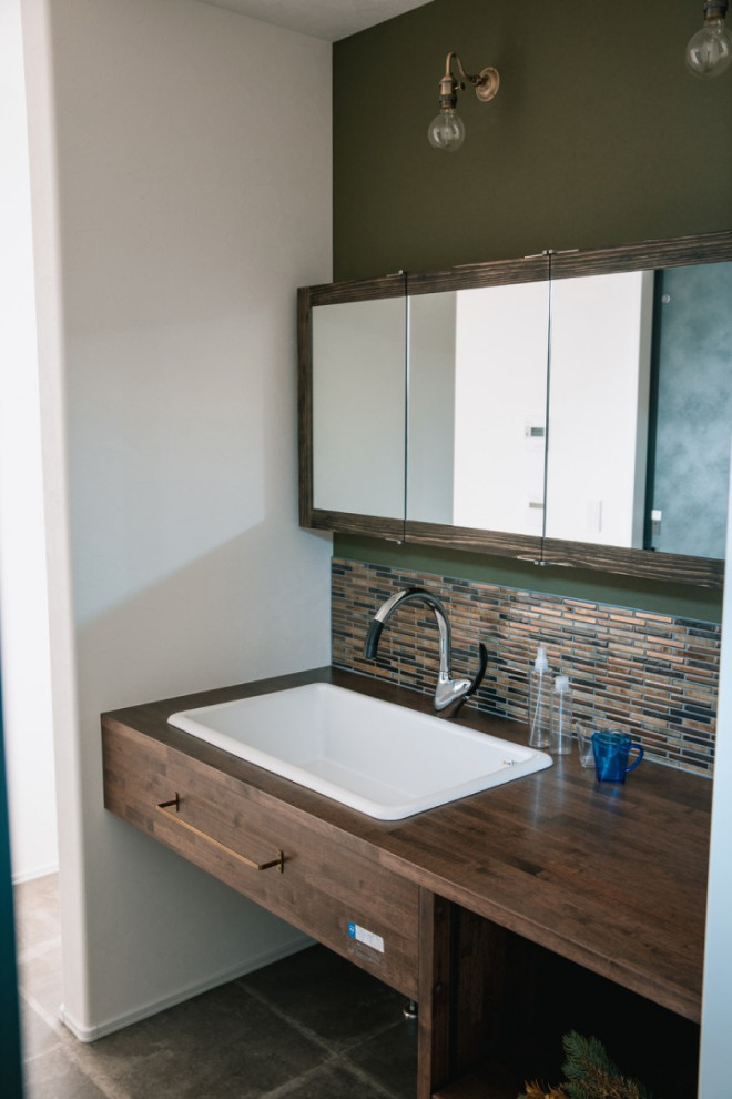 Inspiration pour un WC et toilettes rustique en bois foncé avec un mur vert, un sol gris, un plan de toilette marron, meuble-lavabo encastré et du papier peint.