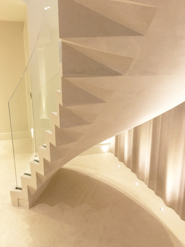 Foto de escalera suspendida actual con escalones de piedra caliza, contrahuellas de piedra caliza y barandilla de vidrio