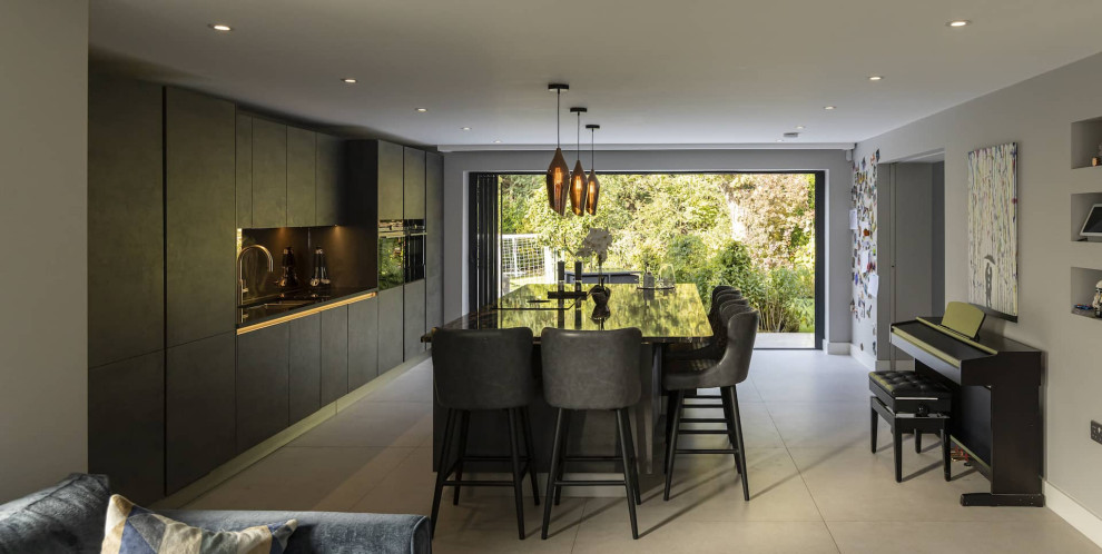 Design ideas for a large modern grey and black single-wall open plan kitchen in Hertfordshire with a double-bowl sink, flat-panel cabinets, black cabinets, granite worktops, metallic splashback, mirror splashback, black appliances, ceramic flooring, an island, white floors, black worktops and feature lighting.