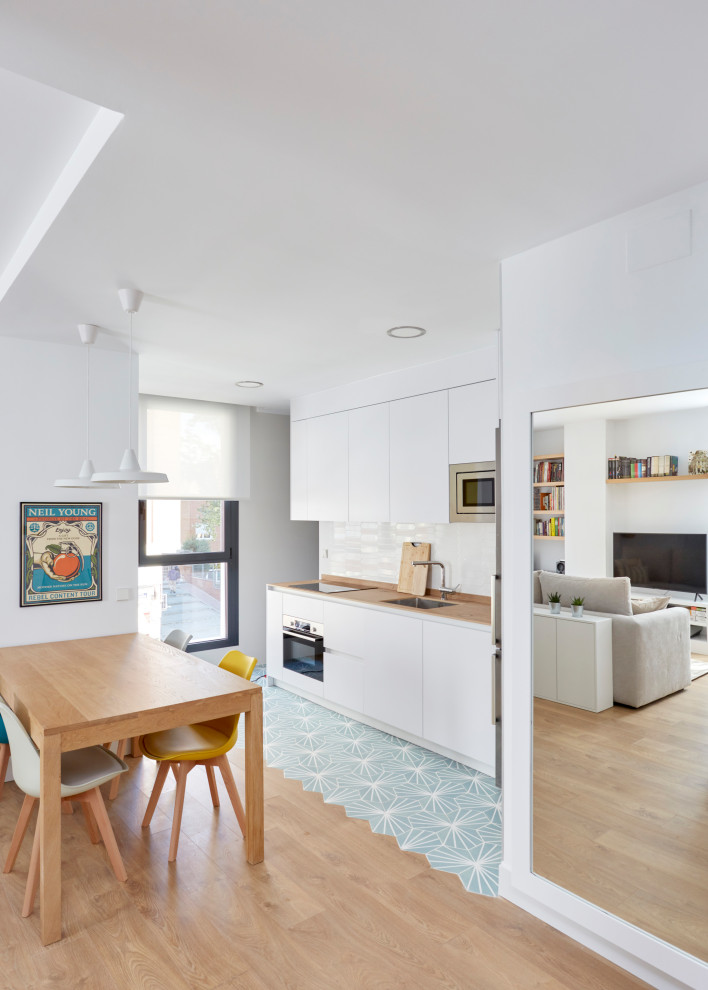 Mid-sized contemporary l-shaped open plan kitchen in Madrid with a single-bowl sink, flat-panel cabinets, white cabinets, granite benchtops, white splashback, ceramic splashback, white appliances, ceramic floors, turquoise floor, grey benchtop and no island.