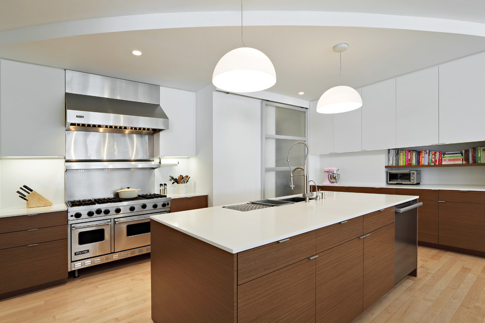 Inspiration for a large modern u-shaped eat-in kitchen in New York with stainless steel appliances, flat-panel cabinets, white splashback, light hardwood floors, with island, an undermount sink, white cabinets, solid surface benchtops and metal splashback.
