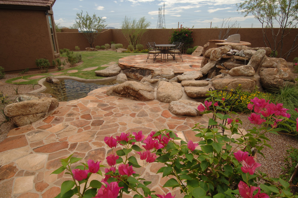 This is an example of a large modern backyard patio in Phoenix with a water feature, stamped concrete and no cover.