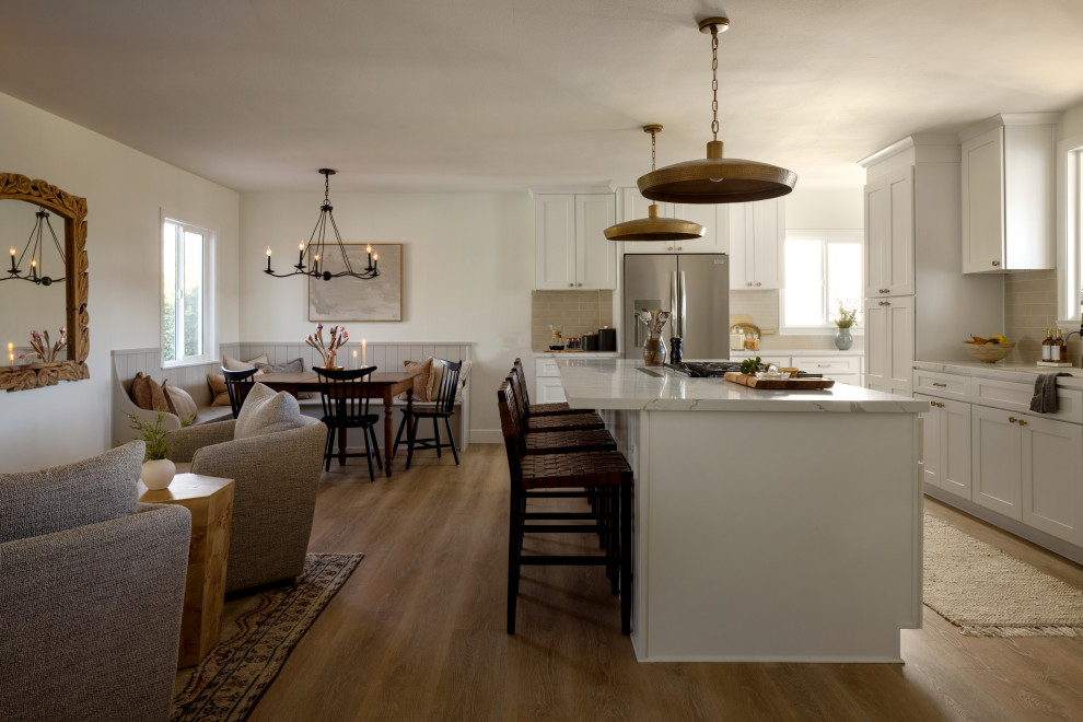 Kitchen - transitional laminate floor and beige floor kitchen idea in Orange County with an undermount sink, shaker cabinets, white cabinets, quartzite countertops, beige backsplash, ceramic backsplash, stainless steel appliances, an island and white countertops