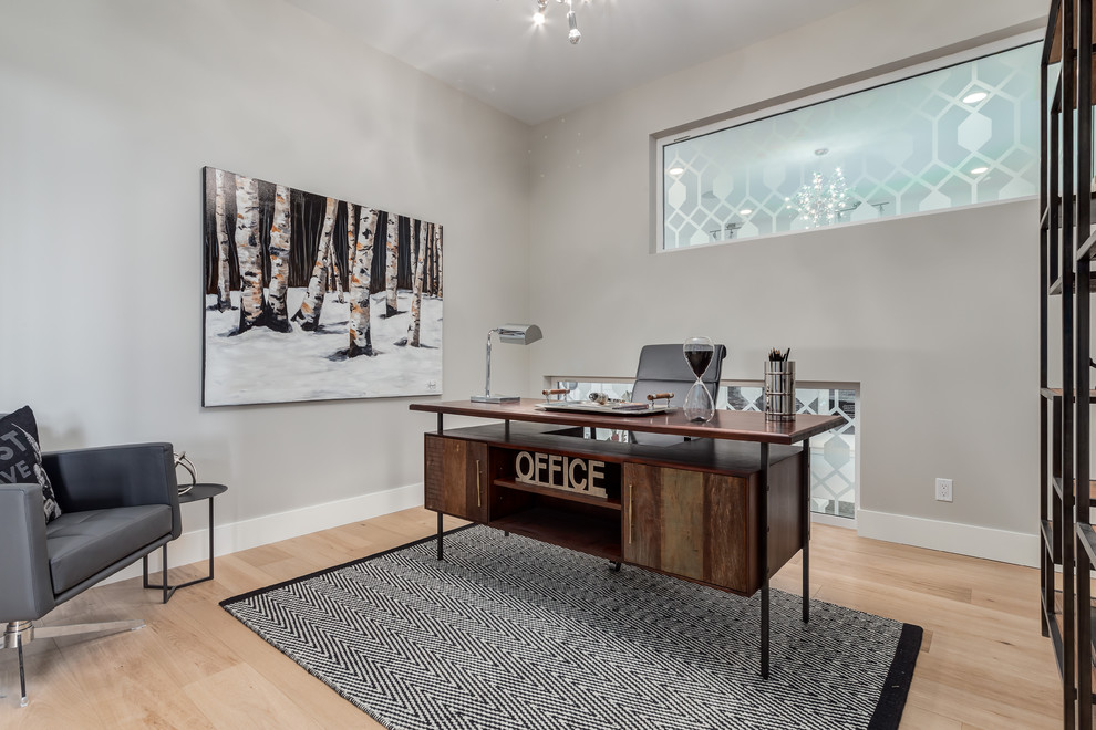 This is an example of a contemporary home office in Calgary with light hardwood floors.