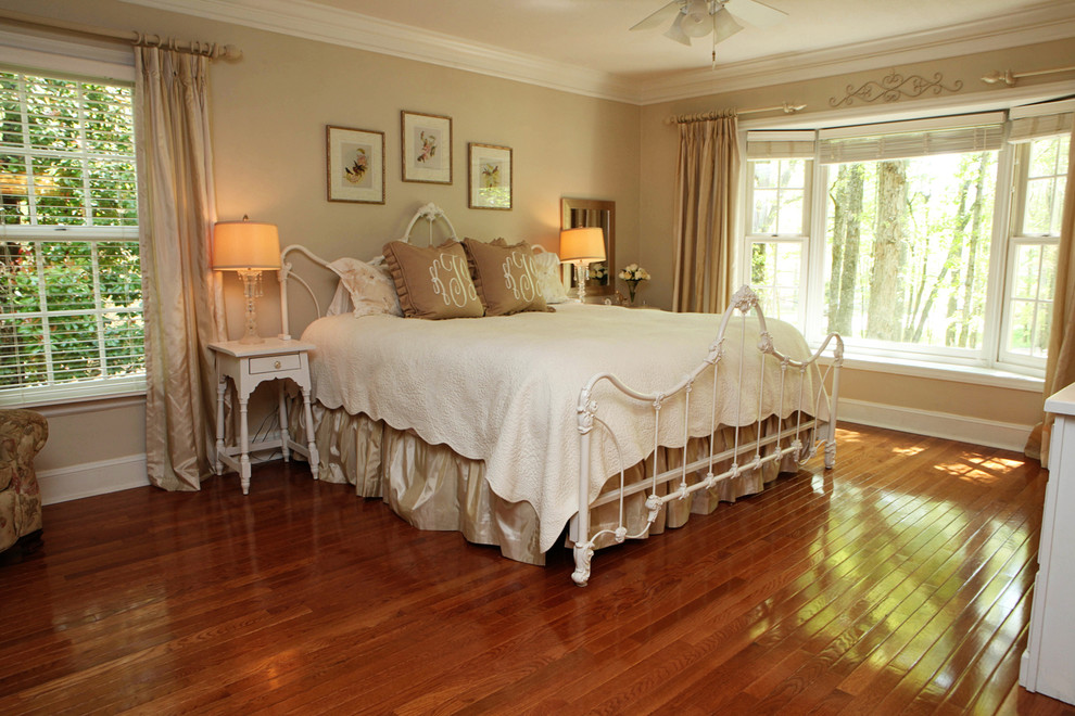 This is an example of a country master bedroom in Charlotte with beige walls and medium hardwood floors.
