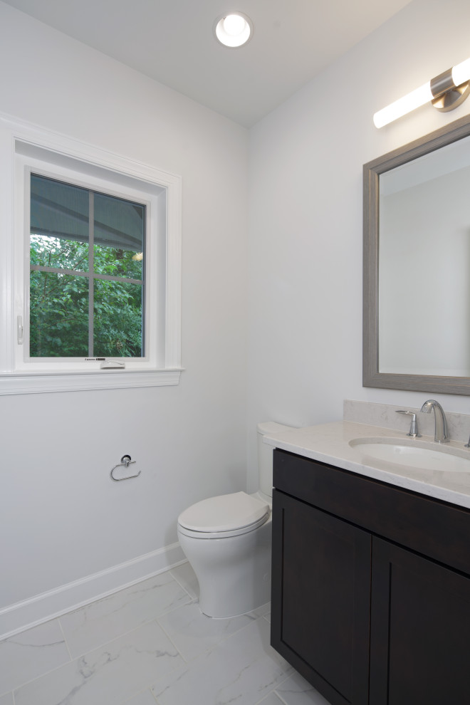 Small transitional powder room in DC Metro with dark wood cabinets, a one-piece toilet, white walls, white floor, white benchtops, a built-in vanity and an undermount sink.