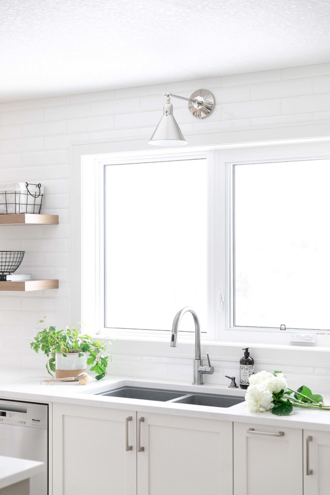 Inspiration for a large transitional u-shaped medium tone wood floor and brown floor eat-in kitchen remodel in Calgary with an undermount sink, shaker cabinets, white cabinets, quartzite countertops, white backsplash, subway tile backsplash, stainless steel appliances, an island and white countertops