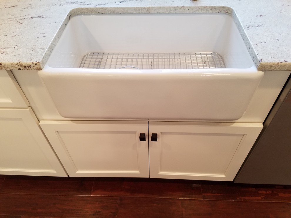 Inspiration for a mid-sized transitional l-shaped dark wood floor and brown floor eat-in kitchen remodel with a farmhouse sink, shaker cabinets, white cabinets, granite countertops, white backsplash, subway tile backsplash, stainless steel appliances and an island