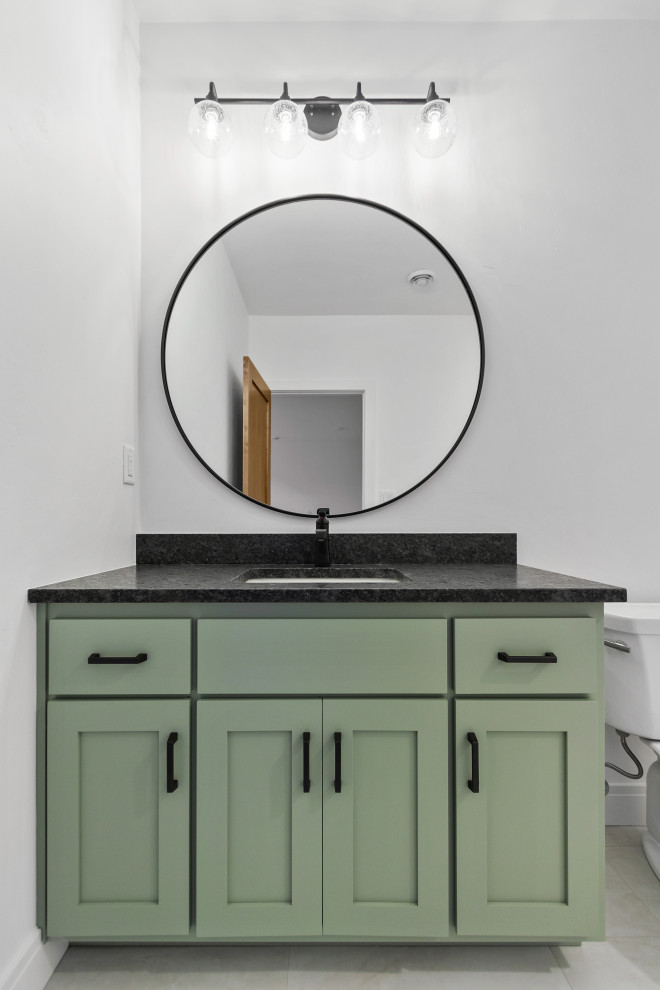 Medium sized classic shower room bathroom in Other with shaker cabinets, green cabinets, a two-piece toilet, white walls, vinyl flooring, a submerged sink, granite worktops, black worktops and a single sink.