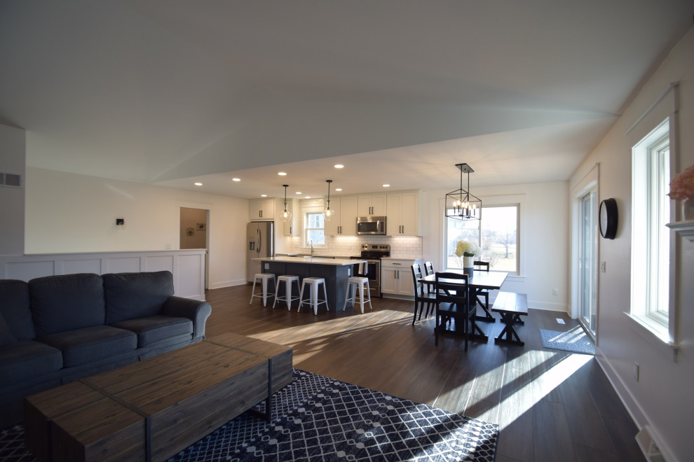 Inspiration for a mid-sized transitional single-wall vinyl floor open concept kitchen remodel with a farmhouse sink, shaker cabinets, quartz countertops, white backsplash, subway tile backsplash, stainless steel appliances, an island and white countertops