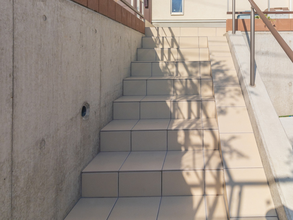 This is an example of a mid-sized contemporary tile straight staircase in Yokohama with tile risers and metal railing.