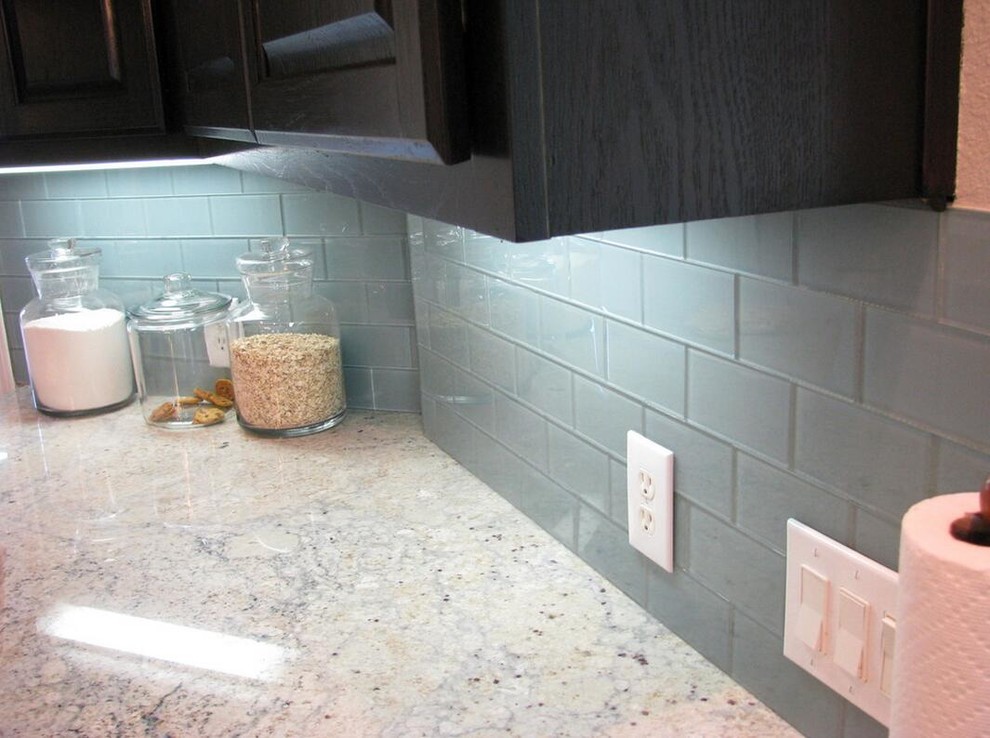 Kitchen - transitional medium tone wood floor kitchen idea with flat-panel cabinets, white cabinets, solid surface countertops, blue backsplash, glass tile backsplash and stainless steel appliances