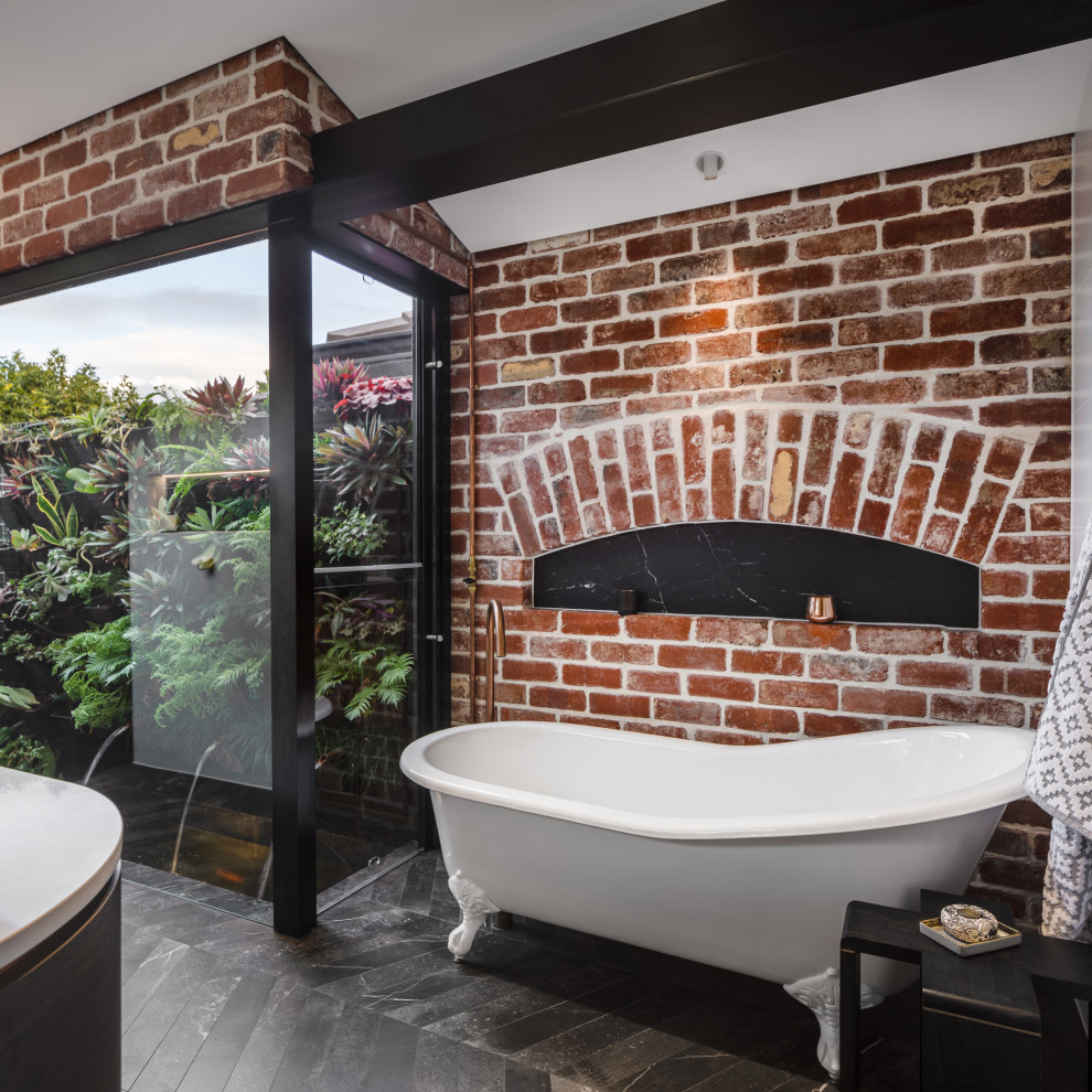 This is an example of an industrial bathroom in Perth with a claw-foot tub, engineered quartz benchtops, white benchtops and black floor.