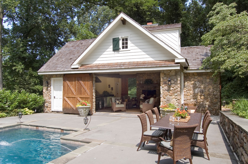Traditional pool in Philadelphia with concrete slab and a pool house.