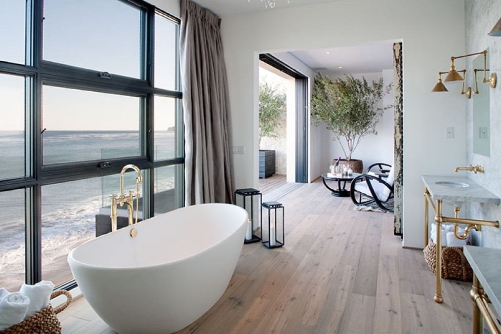 Large transitional master multicolored tile and stone tile light wood floor freestanding bathtub photo with white walls, an undermount sink and marble countertops