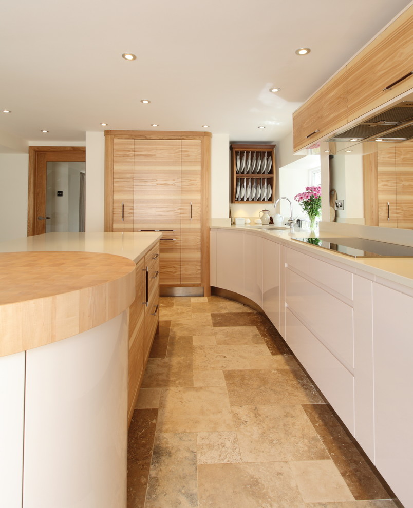 Photo of a mid-sized contemporary l-shaped eat-in kitchen in Manchester with an undermount sink, flat-panel cabinets, light wood cabinets, quartz benchtops, glass sheet splashback, stainless steel appliances, travertine floors and beige floor.