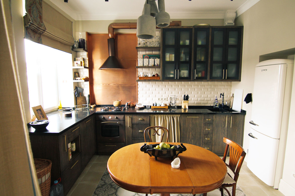 Photo of a mid-sized industrial l-shaped eat-in kitchen in Moscow with a double-bowl sink, flat-panel cabinets, dark wood cabinets, solid surface benchtops, white splashback, black appliances, ceramic floors, no island and subway tile splashback.