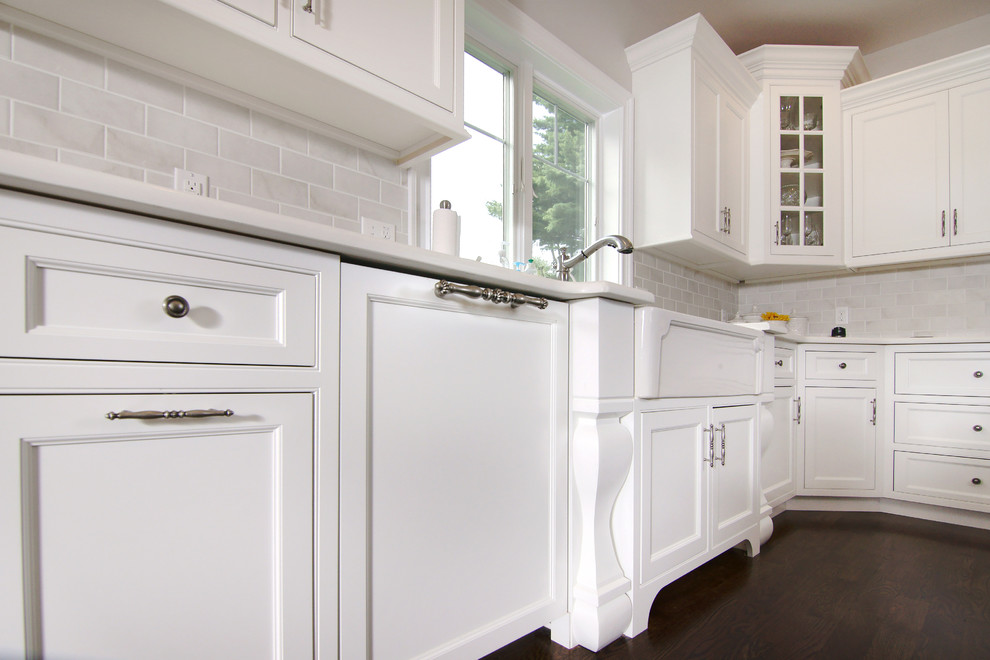 Inspiration for a large transitional u-shaped dark wood floor eat-in kitchen remodel in New York with white cabinets, white backsplash, an island, a farmhouse sink, beaded inset cabinets, subway tile backsplash and paneled appliances