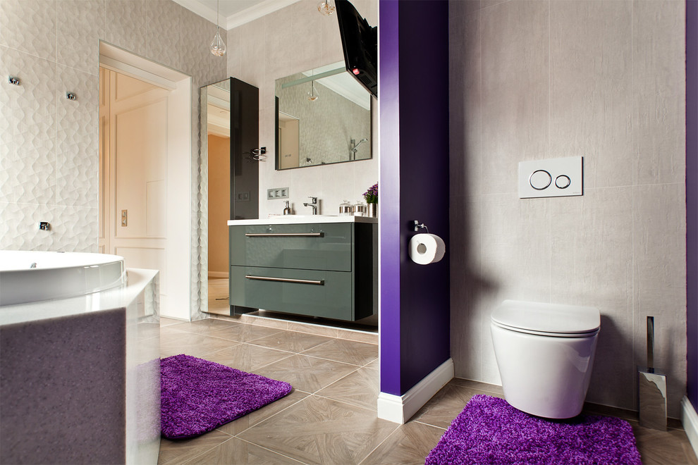 Photo of a mid-sized contemporary bathroom in Moscow with flat-panel cabinets, grey cabinets, a drop-in tub, a wall-mount toilet, gray tile, ceramic tile, purple walls, ceramic floors, a drop-in sink and solid surface benchtops.
