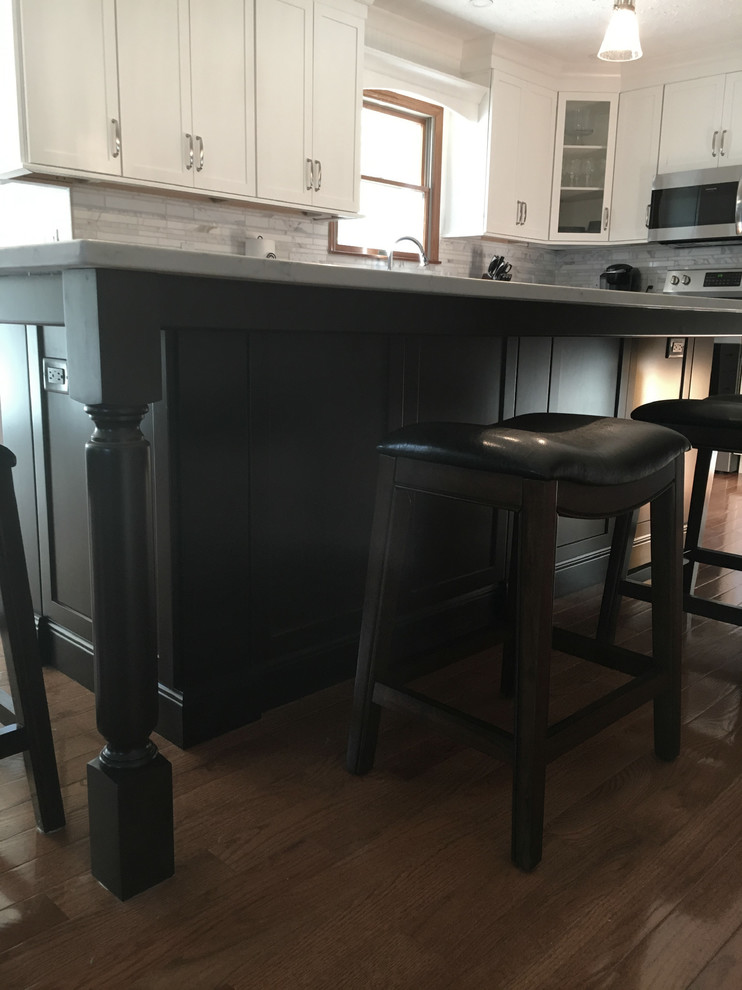 Inspiration for a large transitional single-wall medium tone wood floor eat-in kitchen remodel with an undermount sink, shaker cabinets, white cabinets, granite countertops, multicolored backsplash, marble backsplash, stainless steel appliances, an island and black countertops