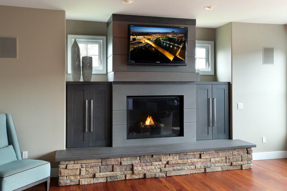 Contemporary living room in Grand Rapids with light hardwood floors, a standard fireplace, a concrete fireplace surround and a wall-mounted tv.