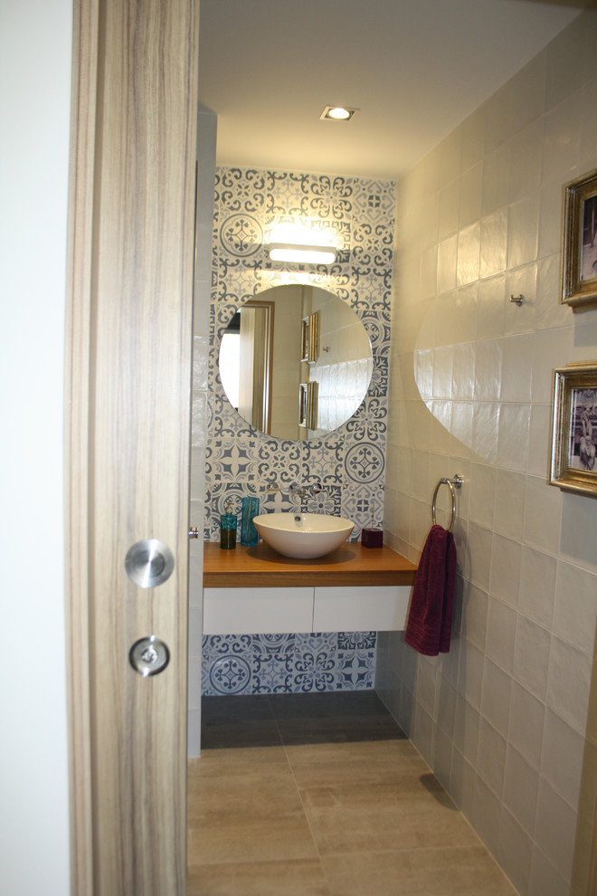 Imagen de aseo moderno pequeño con armarios tipo mueble, puertas de armario blancas, sanitario de una pieza, baldosas y/o azulejos multicolor, baldosas y/o azulejos de cerámica, paredes multicolor, suelo de baldosas de porcelana, lavabo sobreencimera, encimera de madera, suelo gris y encimeras marrones