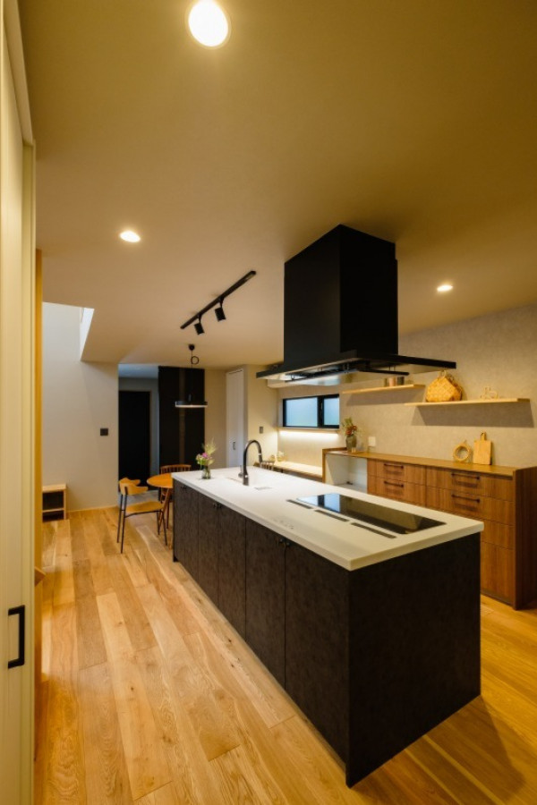 Bild på ett svart linjärt svart kök med öppen planlösning, med mellanmörkt trägolv och en köksö
