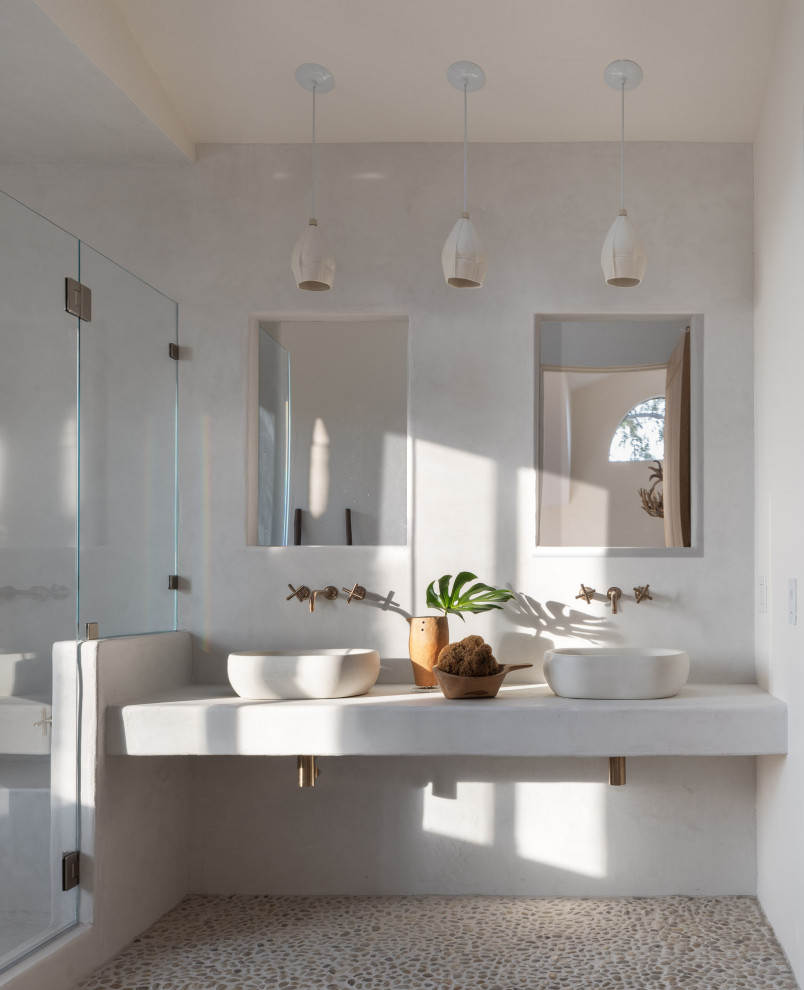 Idée de décoration pour une salle de bain sud-ouest américain avec un mur blanc, un sol en galet, une vasque, un sol beige, un plan de toilette blanc et meuble double vasque.