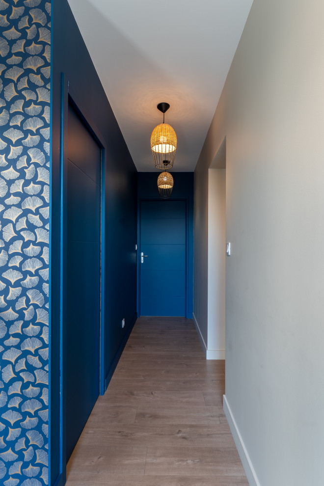 Пример оригинального дизайна: большой коридор в стиле фьюжн с синими стенами, полом из ламината и обоями на стенах