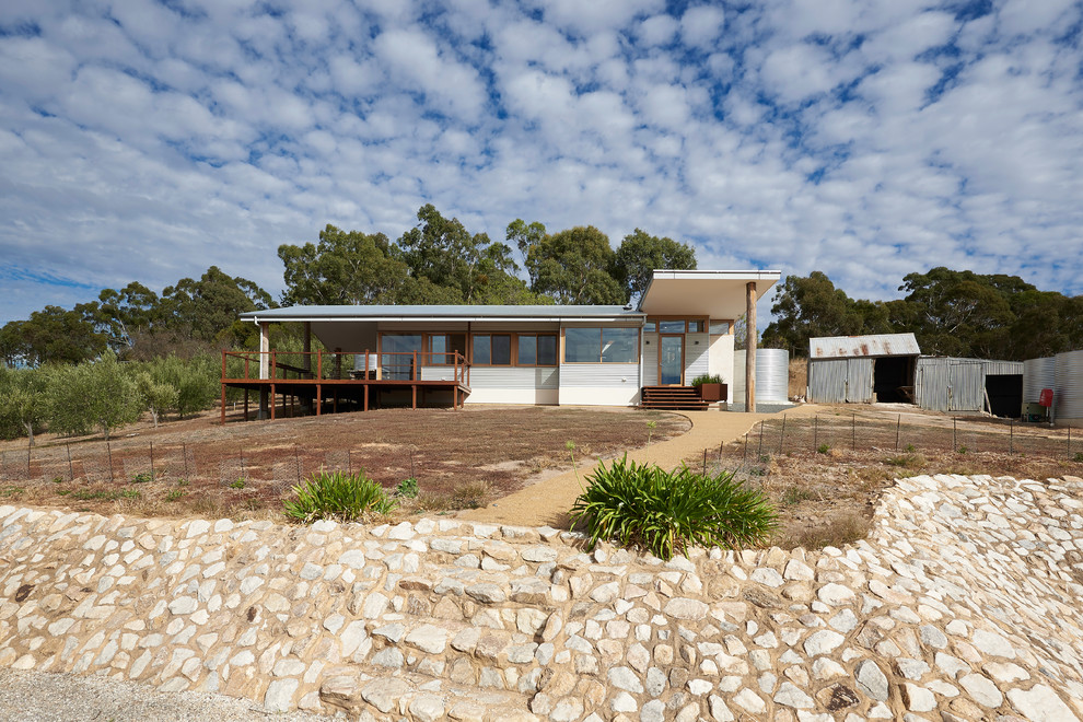 Mid-sized contemporary one-storey adobe beige house exterior in Adelaide with a gable roof and a metal roof.