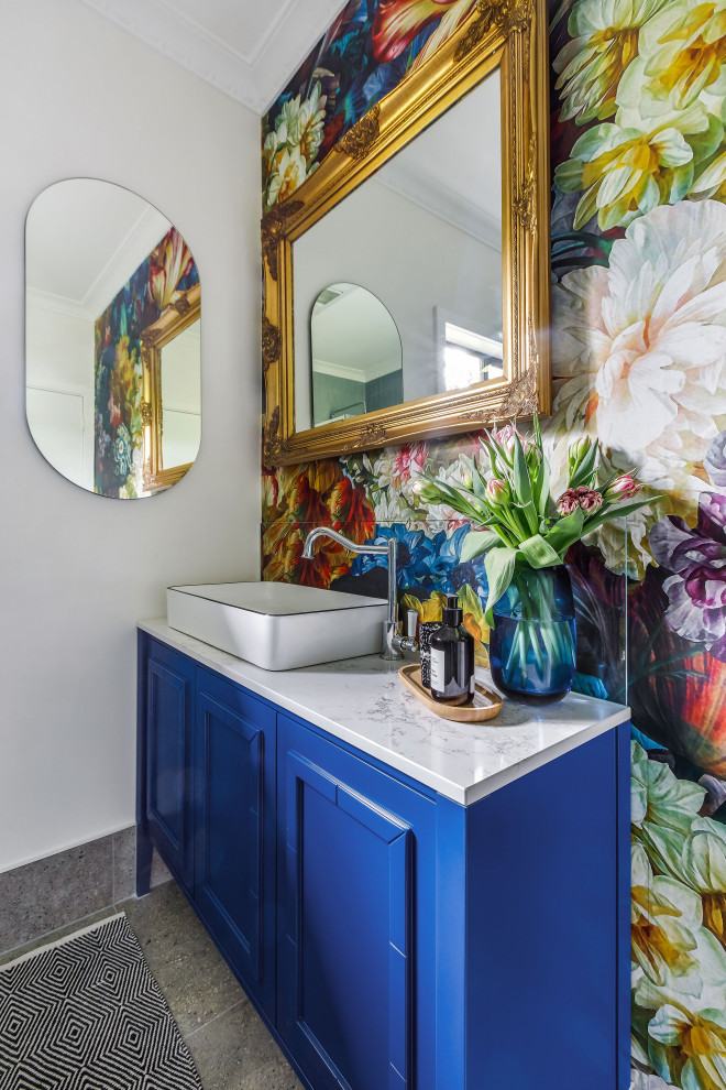 Mid-sized eclectic bathroom in Melbourne with shaker cabinets, blue cabinets, multi-coloured walls, ceramic floors, a vessel sink, engineered quartz benchtops, a hinged shower door, a single vanity, a freestanding vanity and wallpaper.
