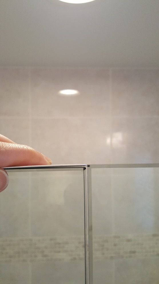 Top of frameless shower glass door not level with fixed panel