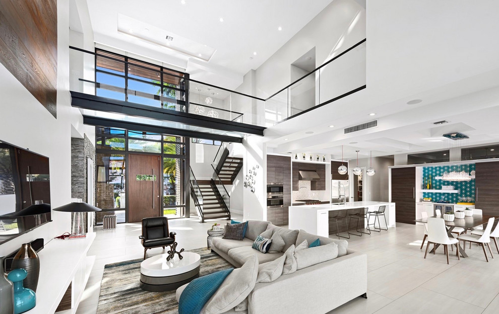 This is an example of a large contemporary open concept living room in Tampa with white walls, porcelain floors, a wall-mounted tv and grey floor.