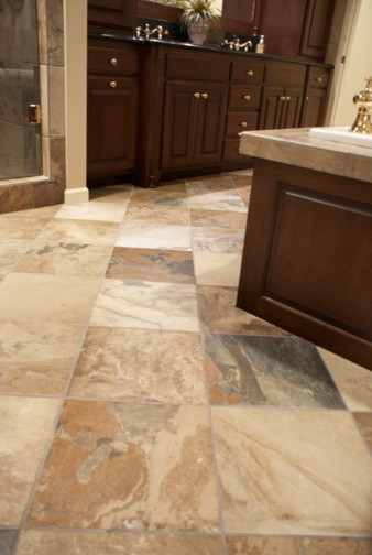 Large transitional master beige tile, gray tile and stone tile travertine floor and beige floor drop-in bathtub photo with raised-panel cabinets, dark wood cabinets, beige walls, an undermount sink and granite countertops
