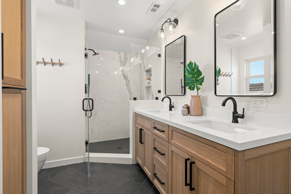 This is an example of a medium sized retro ensuite bathroom in San Francisco with shaker cabinets, light wood cabinets, an alcove shower, a one-piece toilet, white tiles, marble tiles, white walls, slate flooring, a submerged sink, quartz worktops, black floors, a hinged door, white worktops, a wall niche, double sinks and a floating vanity unit.