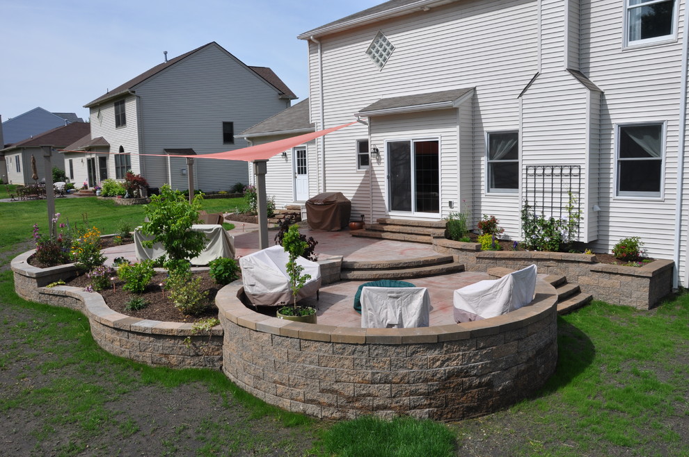 This is an example of a large traditional backyard patio in Cleveland with concrete pavers and an awning.